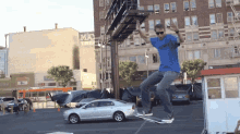 a man in a blue shirt is doing a trick on a skateboard in front of a building that says mad