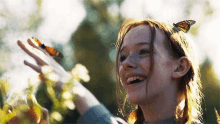 a young girl is holding a butterfly in her hand .