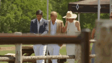 a man in a suit and a woman in a hat are standing in front of an aspen valley tent