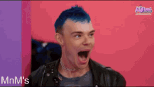 a man with blue hair is making a funny face while wearing a leather jacket .