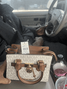 a person is sitting in a car with a michael kors purse on their lap