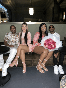 a group of people sitting on a couch with one woman holding a bouquet of pink flowers