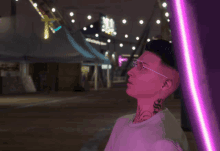 a man with glasses and a tattoo on his neck looks up at a purple light