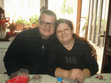 a man and a woman are posing for a picture and the woman is wearing a black shirt that says mm