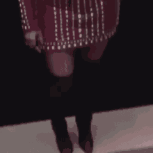 a woman in a red dress and black boots is standing on a stage in front of a black wall .