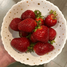 a white bowl filled with strawberries with gold stars on it