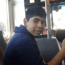 a young boy is sitting on a bus looking at the camera and smiling .