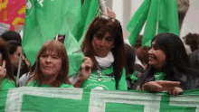 a group of women are holding green flags and one of them is wearing a green shirt with the letter t on it