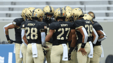 a group of army football players huddle in a huddle