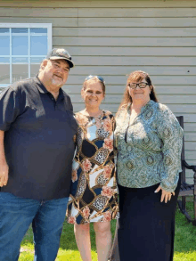 a man and two women stand in front of a house