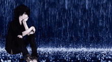 a young boy is sitting in the rain with his hand on his face .