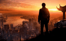 a man stands on top of a hill overlooking a city