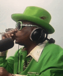 a man wearing a green hat and headphones is blowing into a trumpet