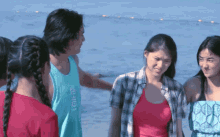 a group of people standing on a beach with one wearing a shirt that says ' hawaii ' on it