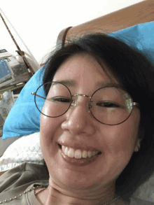 a woman wearing glasses is smiling while laying in bed