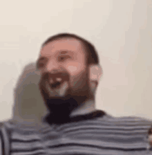 a man with a beard is wearing a striped shirt and laughing .