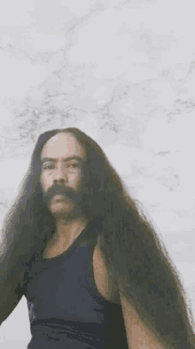 a man with long hair and a mustache wearing a black tank top