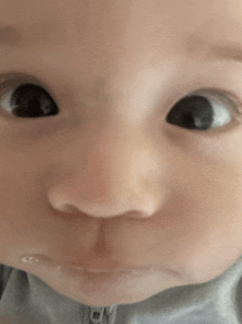 a close up of a baby 's face with a gray shirt that says cy