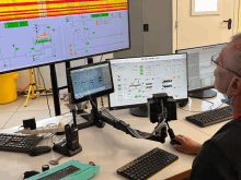 a man wearing a mask is sitting at a desk in front of a monitor that says ' siemens ' on the top