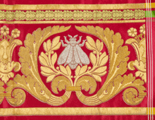 a close up of a red and gold embroidery with a bee on it