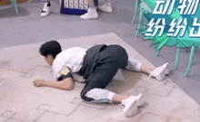 a man is kneeling on the floor with his legs crossed and a sign in the background .