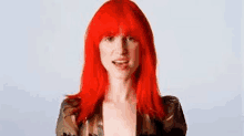 a woman with red hair is wearing a black jacket and making a face .