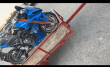 a blue suzuki motorcycle is sitting on a wooden trailer