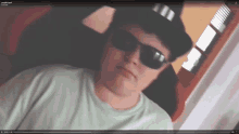 a man wearing sunglasses and a hat is on a screen that says ' penguins.mp4 ' on it