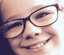 the girl is wearing glasses and smiling for the camera .