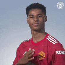 a young man wearing a red manchester united shirt is clapping his hands .