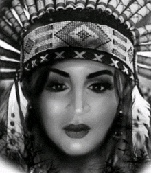 a black and white portrait of a woman wearing a native american headdress