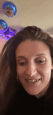 a close up of a woman 's face in front of balloons