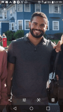 a man with a beard smiles in front of a blue building