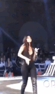 a woman in a black bodysuit is dancing on a stage in front of a crowd