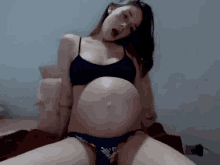 a pregnant woman in lingerie is sitting on a bed with her mouth open .