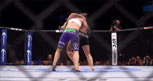 two women are fighting in a ufc ring while a crowd watches .