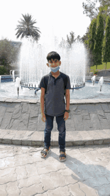 a young boy wearing a mask is standing in front of a fountain