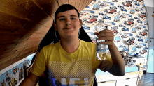 a young man holding a bottle of water in front of a race car wallpaper