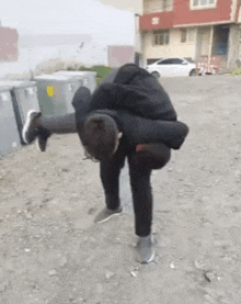 a young man is doing a handstand in a dirt field .