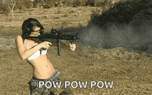 a woman in a bikini is holding a gun in a field and says pow pow pow