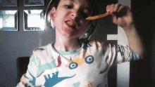 a young boy wearing headphones is eating a french fry