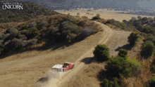 an aerial view of a truck driving down a dirt road with the words wish you a unicorn above it