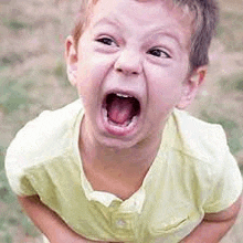 a young boy is making a funny face with his mouth open and his tongue hanging out .