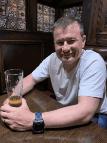 a man is sitting at a table with a glass of beer in his hand