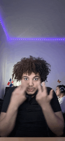 a man with curly hair is making a funny face with his fingers