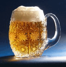 a glass mug filled with beer and foam on a blue surface