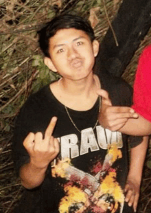 a young man wearing a raw t-shirt shows the middle finger