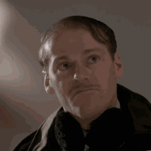 a man with a mustache is wearing a black coat