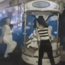 two women are standing in front of a carousel .