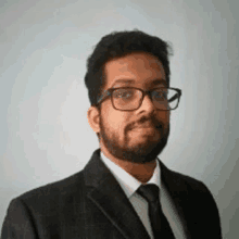 a man with a beard wearing glasses and a suit and tie